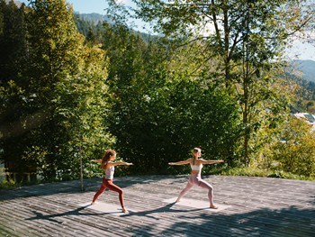 Ganzjährig Yoga genießen, auch im Freien Zwei Frauen machen Yoga auf einer Terrasse